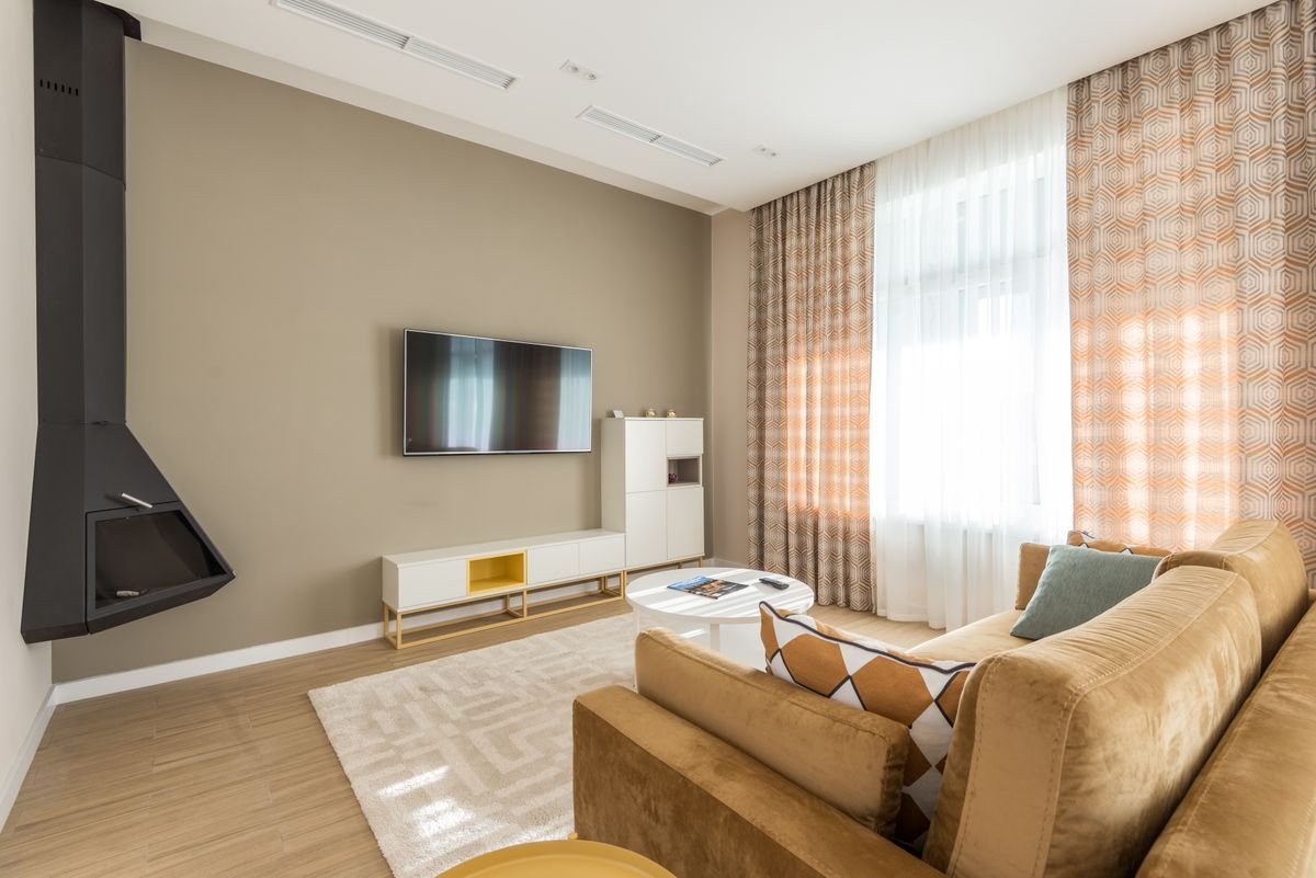 Inspiration: a mounted TV in a warm living room with tan sofas and sheer curtains